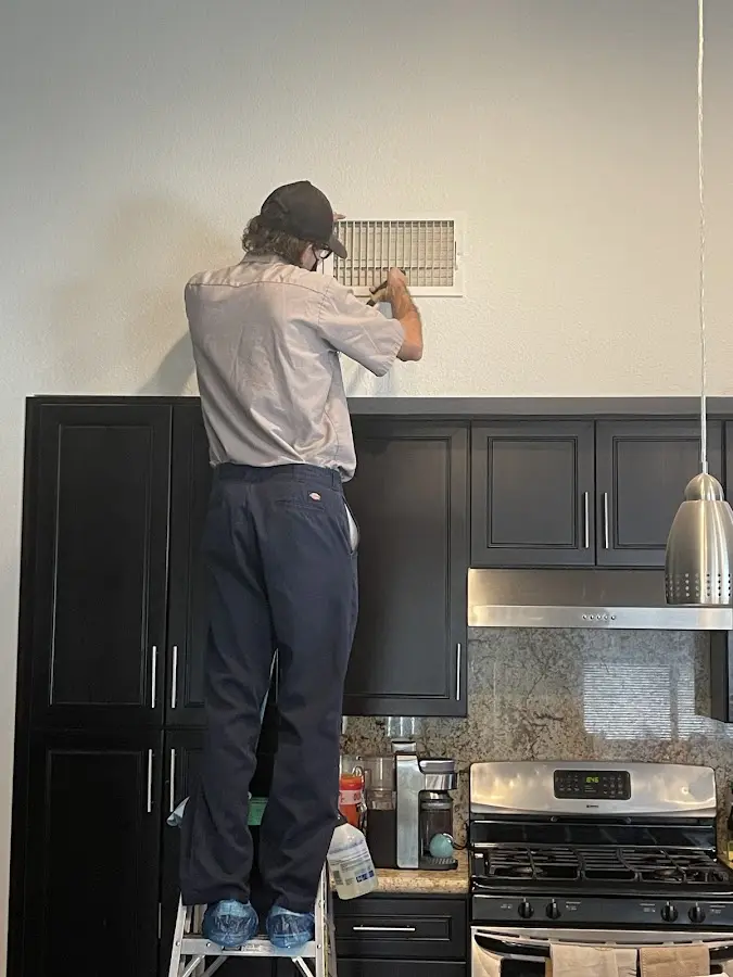Technician inspecting an air vent during HVAC service in Horseshoe Bay